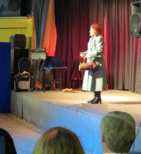 Judith Hibbert on stage in coat