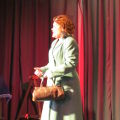 Judith Hibbert on stage in coat